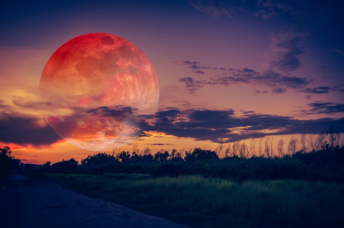 Vollmond in rötlichem Licht steht am Sommerhimmel
