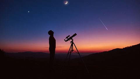 Mann schaut mit dem Sternengucker in den Nachthimmel zu einer Mondfinsternis - Foto: m-gucci / iStock