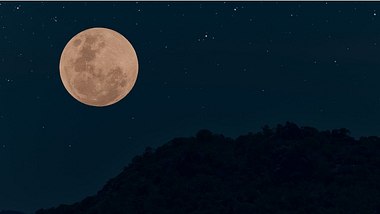 Vollmond am Nachthimmel mit Bergsilhouette - Foto: iStock/Onkamon Buasorn