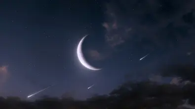 An einem Nachthimmel ist groß leuchtenden die Neumond-Sichel zu sehen. Außerdem erleuchten drei Sternschnuppen den dunkel Nachthimmel. - Foto: Nazarii Neshcherenskyi/iStock