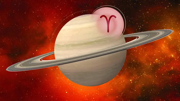 Eine Grafik des Planeten Saturn mit dem Symbol des Sternzeichens Widder sind vor einem roten kosmischen Hintergrund zu sehen.  - Foto: Astrowoche.de & iStock (Nerthuz + iosebi meladze)