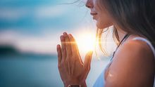 Frau hält bei Sonnenuntergang Hände in Gebetshaltung - Foto: iStock/microgen