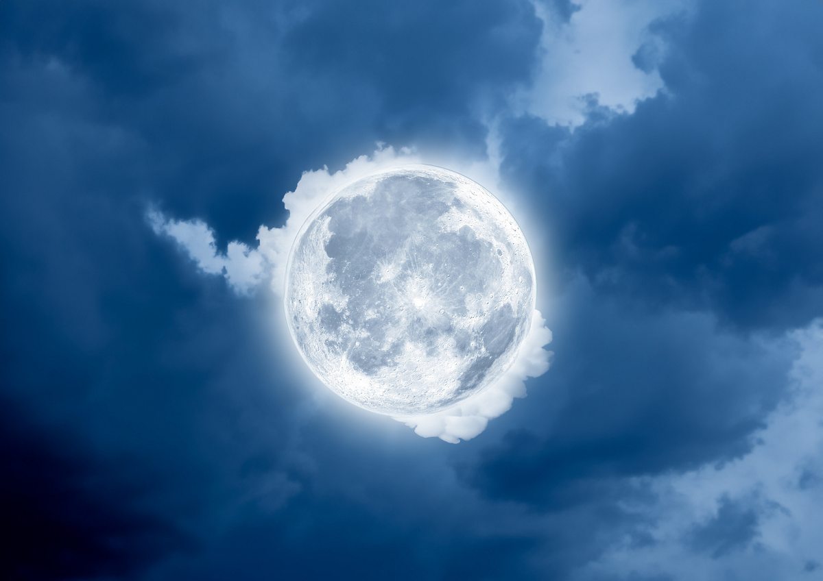 Vollmond steht von Wolken umgeben am Himmel